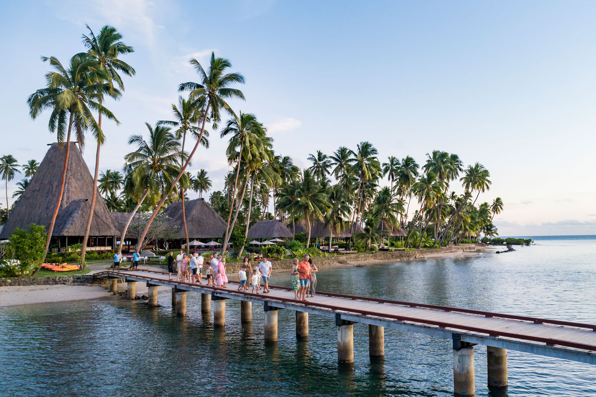 Multigenerational-1-Large-Family-Vacation-Fiji Image shows a multigenerational family walking down the jetty at sunset at Jean-Michel Cousteau Resort Fiji, an all-inclusive family resort in Fiji.